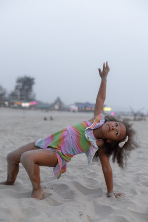 Childrens health gymnastics. Charming African American girl is doing sports on summer at beach.の写真素材