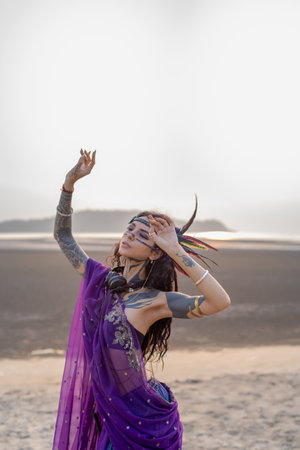 A happy woman in a magenta dress dances on the beach under the sky