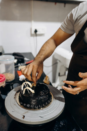 Unrecognizable male chef decorates candied chocolate cake. Small business entrepreneurship.の写真素材