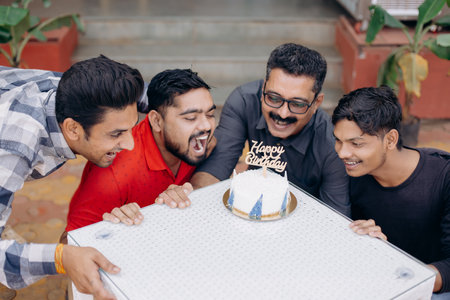 Friends celebrating a birthday with a cake in an outdoor garden, sharing joy and bondingの写真素材