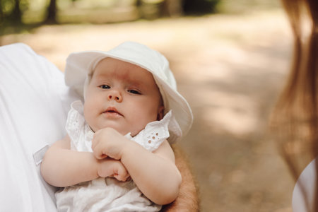 a woman is holding a baby in her arms wearing a white hatの写真素材