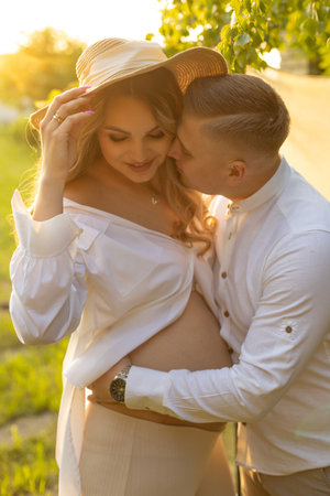 A man is kissing a pregnant woman on the cheek at a happy eventの写真素材