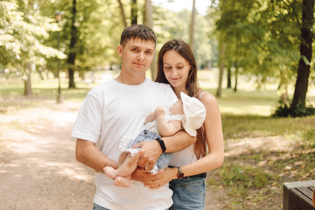 a man and woman are holding a baby in a parkの写真素材