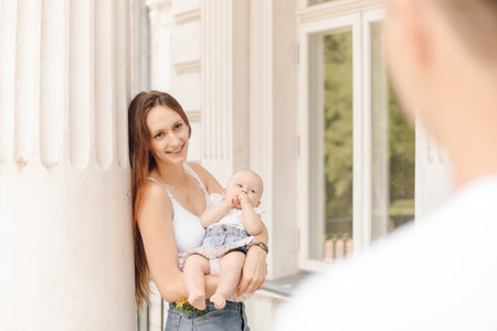 a woman is holding a baby in her arms while a man looks onの写真素材