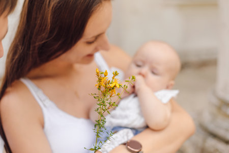 A woman shares a happy gesture holding a baby and a bouquet of flowersの写真素材