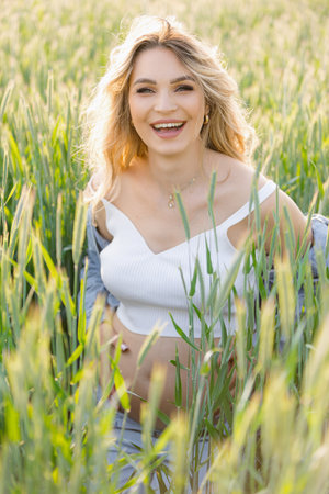 a pregnant woman is standing in a field of tall grassの写真素材