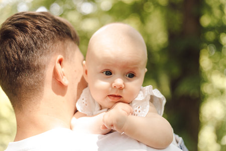 A man happily holding a baby in his arms on the grass in a parkの写真素材