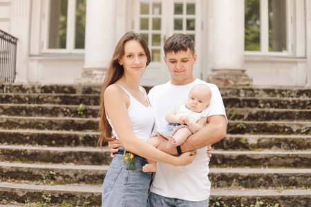 a man and woman are holding a baby in front of a buildingの写真素材