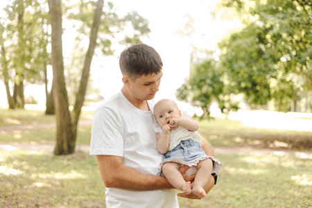 a man is holding a baby in his arms in a parkの写真素材