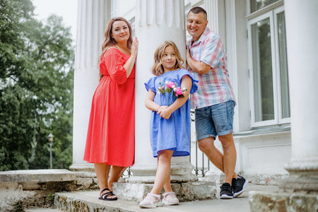A happy family is posing on building steps, with smiles and leisure posesの写真素材