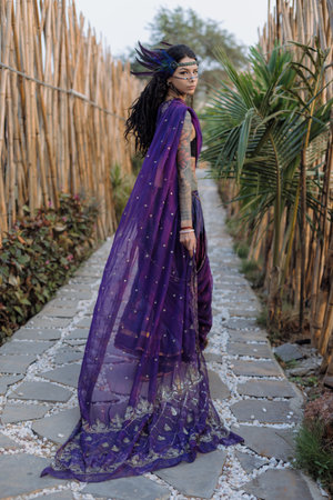 A woman in a purple gown stands on a stone pathway beside a treeの写真素材