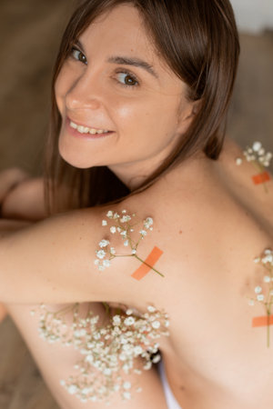 A woman is smiling surrounded by flowers, expressing joy in celebrating nature and beautyの写真素材