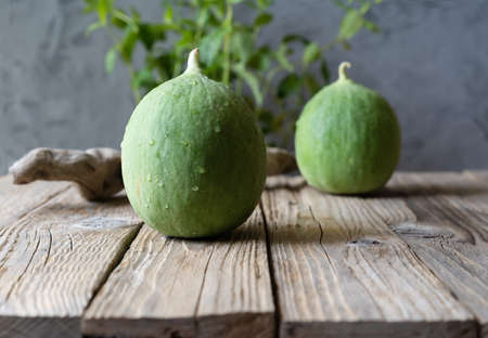 Barattieri are kind of Italian cucumber. Two fruits on the wooden table with mint plant in...