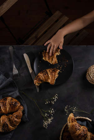 Croissants in low key and child hand taking one of themの写真素材