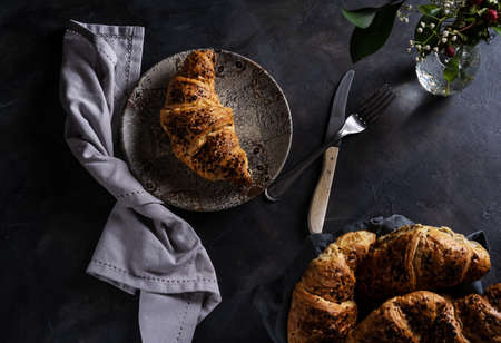 Croissants in low key. One brioche on the plate, pastry group asideの写真素材