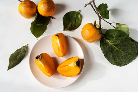 persimmon with leaves and branches on the white backgroundの写真素材