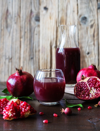 pomegranates juice and fruits with leaves, wooden backgroundの写真素材