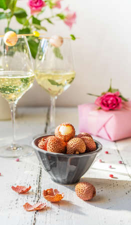 S.Valentines Day concept. Sparkling wine in two glasses, litchi berries, roses and giftの写真素材