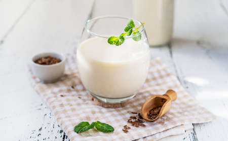 Flaxseed milk in glass and bottle, napkin, flax seeds, mint leaves.の写真素材