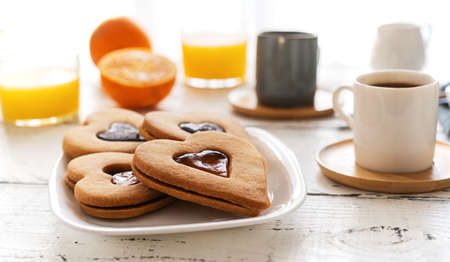 Breakfast concept with coffee, orange juice and cookies in heart shape with jam
