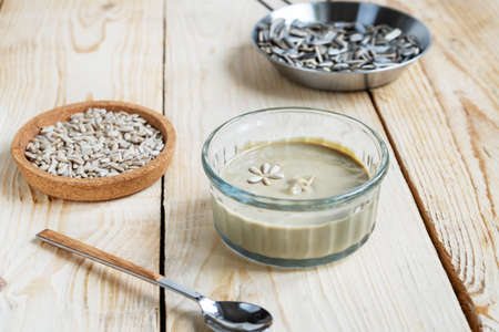 Homemade sunflower seeds butter or spread with roasted seeds on light wooden background