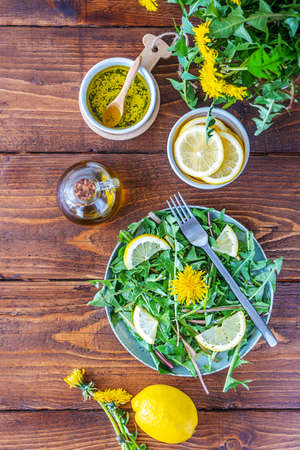 Dandelion salad with dip made with olive oil, lemon juice and spices on brown wooden table. Top viewの写真素材