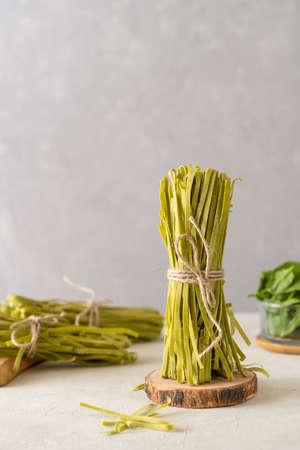 Bundle of raw pasta fettuccine with spinaches on concrete backgroundの写真素材