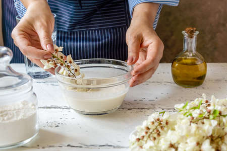 Female hands are dipping Acacia flowers in batter for cooking Acacia fritters