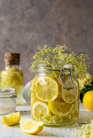 Elderberry infused watering or syrup in jar and bottle made with fresh flowers and lemons as main ingredients. vertical banner. Selective focusの写真素材