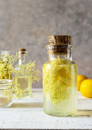 Elderberry infused watering or syrup in jar and bottle made with fresh flowers and lemons as main ingredients. Vertical banner. Selective focusの写真素材