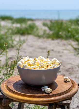 Popcorn in bowl on the beach with sea coast view. Copy space.の写真素材