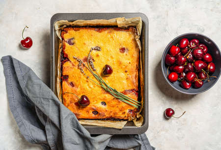 Fresh baked sweet cherry pie or red brownie cake in baking sheet with lavender, napkin and raw berries aside.の写真素材