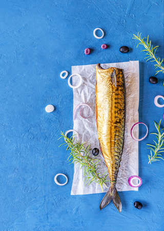 Smoked mackerel with rings of onion, lemon, olives, rosemary on blue background. Top viewの写真素材