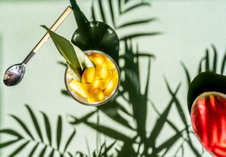Thai dessert with mango and sticky rice and coconut milk decorated by carnation, sugarcane leaf, raw...