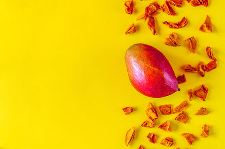 Raw mango with chips over yellow background. Top view with copy spaceの写真素材