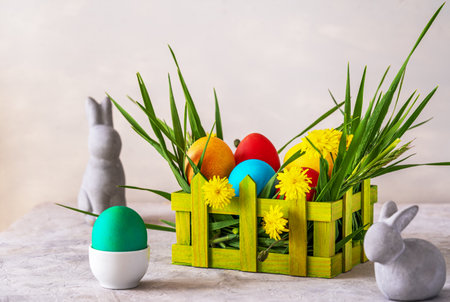 Easter spring decoration with painted eggs, rabbits, field flowers, wooden box and wheatgrass