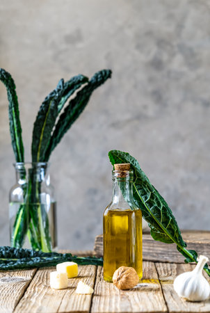 Ingredients for homemade kale - kale leaves, walnuts, parmesan, garlic and olive oil on wooden surface with grey backgroundの写真素材