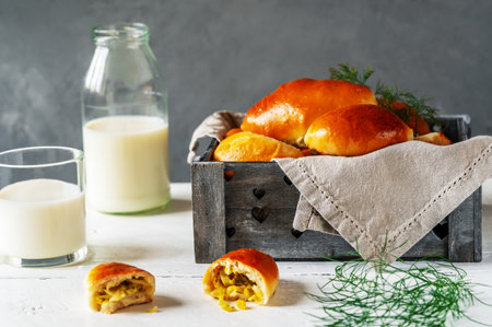 Baked homemade pies with cabbage, greens and eggs in the wooden grey box, milk and dill over white and grey backgroundの写真素材