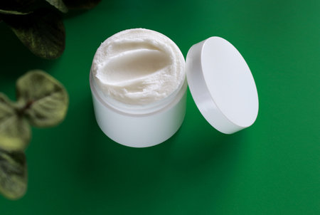 mock up of white jar of cream on a green background, with copy spaceの写真素材