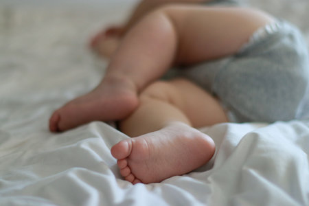 close up of sleeping baby boy 9 months old, bed with white sheets