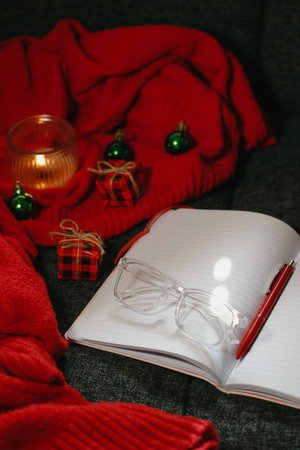 Christmas composition with notebook, pen, glasses, candle and decor