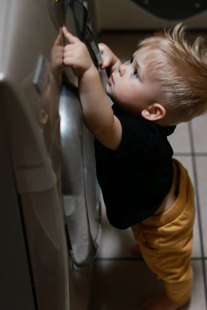 close up of a boy playing with buttons of washing machineの写真素材