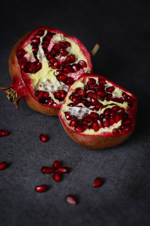 close up of a cut pomegranate on grey table and wooden dark backgroundの写真素材