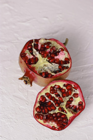 close up of a cut pomegranate on white table with textureの写真素材