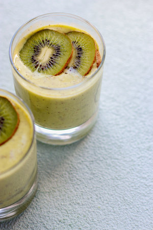 kiwi smoothie in a glass on blue background, blurred backgroundの写真素材