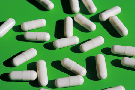 white pills capsules and bottle on green background