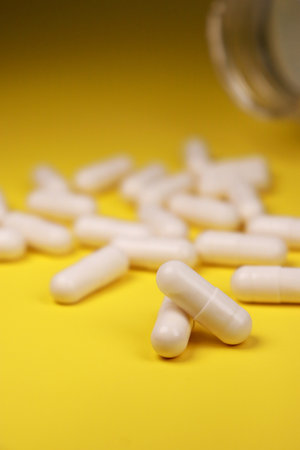 close up of white pills capsules on yellow background