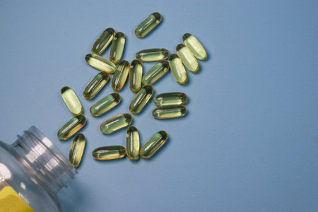 close up of fish oil capsules, blue background with copy space