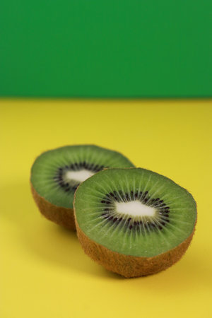 close up of kiwi fruit half on yellow and green background
