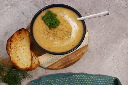 red lentils soup puree in dark bowl with bread on grey marble tableの写真素材